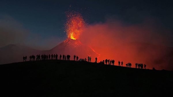 Walkers watch the explosions and cascades of lava from Mount Etna