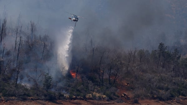 A firefighting helicopter drops water on a wildfire in Oroville, California