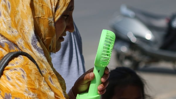 A woman cools off with a battery fan on a hot summer day in Kashmir, India