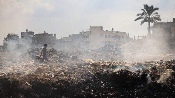 A Palestinian boy walks past piles of smouldering waste, as garbage collection and any other municipality services come to a halt due to Israeli at the al-Maghazi Palestinian refugee camp