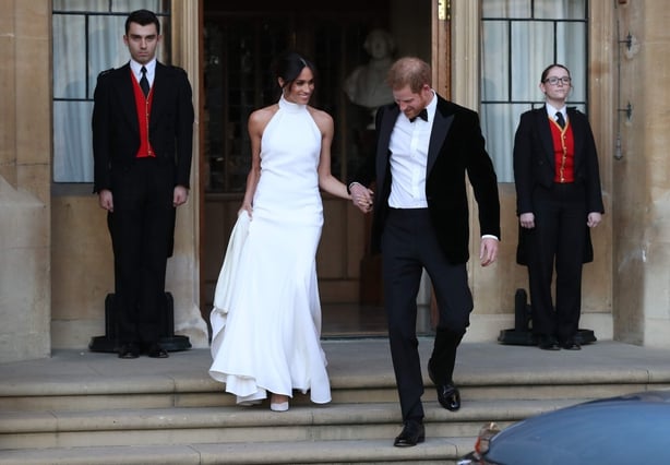 Meghan, Duchess of Sussex and Harry, Duke of Sussex, walk down the steps from Frogmore cottage hours after marrying in their second outfits of the day. Meghan wears a white sleeveless mermaid gown and Harry a black velvet tuxedo