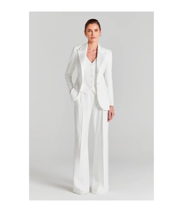 Model wears white three piece suit with wide leg trousers and tailored jacket